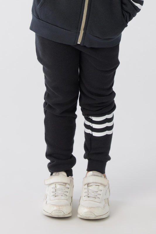 Black joggers with three stripes horizontally in white on the left pant leg