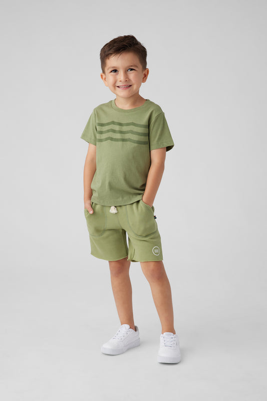 Model image of a boy in a green t-shirt and short set. T-shirt design is of waves