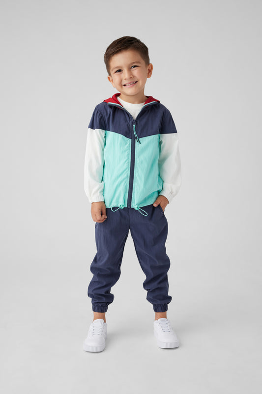 Modeil image of boy in a colorblock zip up hoodie and navy joggers. Zip up is in navy, light blue with red on the inside.